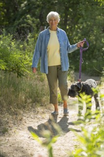 Older Caucasian woman walking dog on dirt path