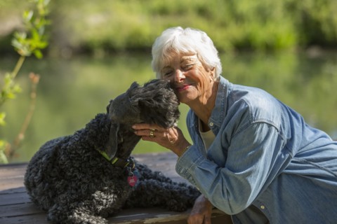 Older Caucasian woman hugging dog in park
