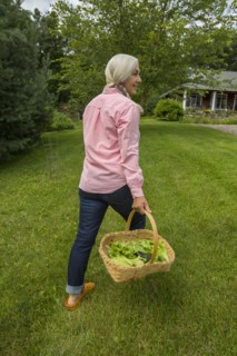 Caucasian woman carrying basket of vegetables in backyard