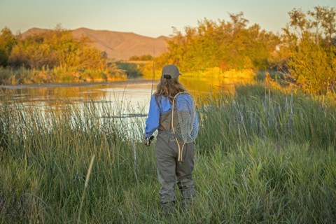 Caucasian woman with fishing gear at river