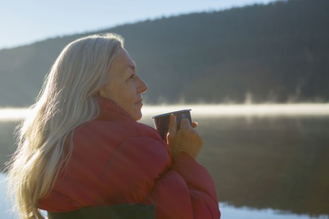 Caucasian woman drinking coffee at lake