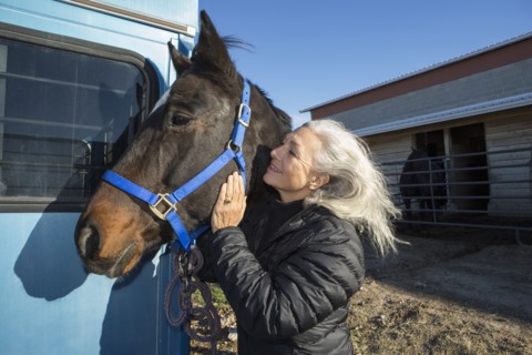 Caucasian woman petting horse on ranch