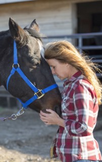 Caucasian woman hugging horse on ranch