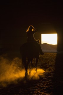 Caucasian woman riding horse in barn