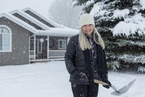 Older Caucasian woman shoveling snow in front yard