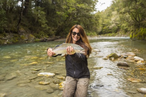 Caucasian woman catching fish in remote river