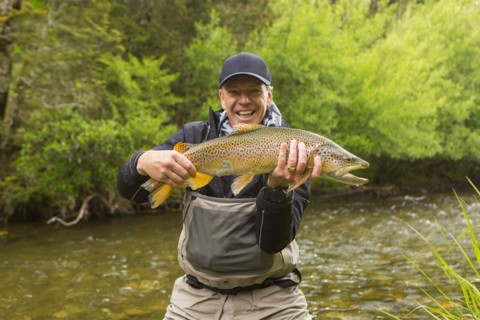 Caucasian man holding fish in remote river