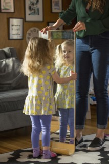 Caucasian mother showing daughter reflection in mirror