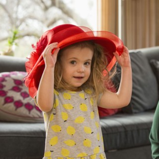Caucasian preschooler girl playing dress-up with hat