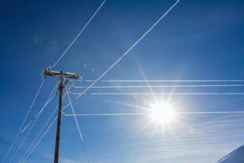 Sun in blue sky and frosty power lines