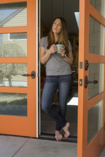 Woman standing barefoot in doorway drinking coffee