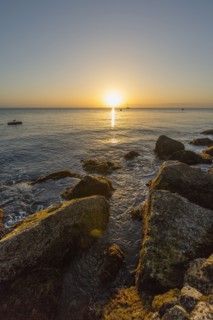 Rocks on ocean beach at sunset