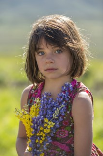Serious Caucasian girl holding bouquet wildflowers