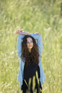 Caucasian woman with arms raised standing in field of tall grass