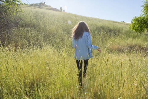 Caucasian woman walking in field of tall grass