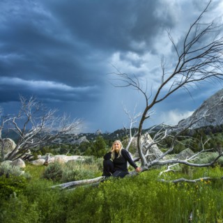 Caucasian woman sitting on fallen tree under clouds