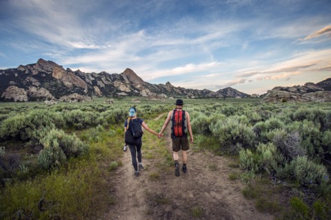 Caucasian couple hiking toward mountain
