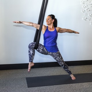 Mixed Race woman performing yoga hanging from silks