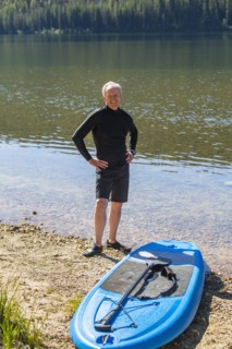 Smiling Caucasian man posing near paddleboard
