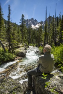 Caucasian man sitting on rock at mountain river