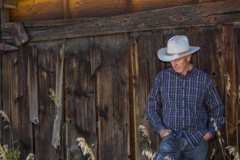 Pensive Caucasian farmer leaning on wooden fence