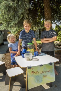 Smiling Caucasian boys and girl selling lemonade