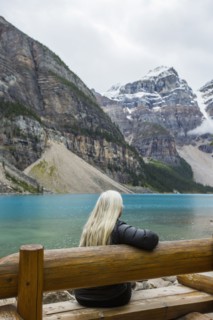 Caucasian woman sitting on bench at mountain lake