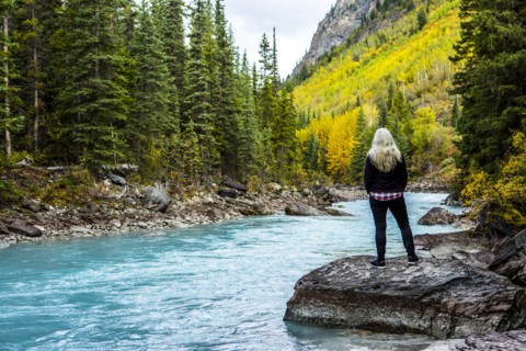 Caucasian woman standing on rock near mountain river
