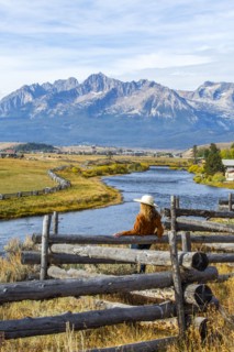 Caucasian woman leaning on wooden fence at mountain river