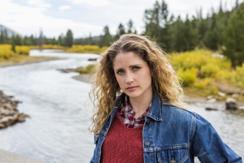 Serious Caucasian woman standing near winding river