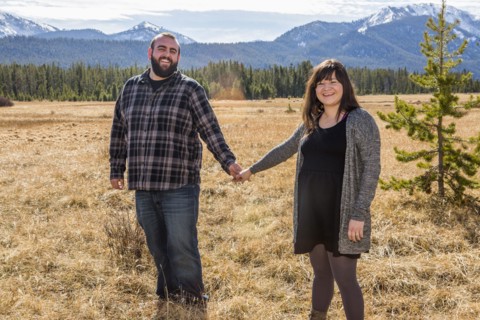 Smiling Caucasian couple holding hands in field