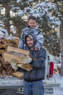 Caucasian father and son carrying firewood from truck