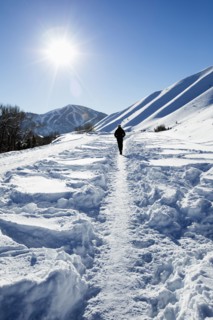 Caucasian man hiking on trail in snow on sunny mountain