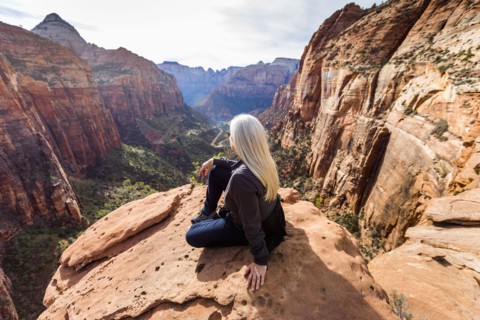 Caucasian woman sitting on rock admiring scenic view of rock formations