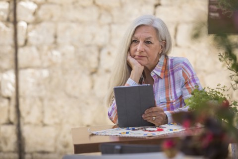 Pensive older Caucasian woman using digital tablet