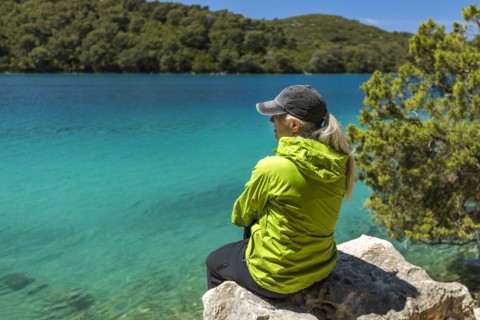 Caucasian woman sitting on rock at lake