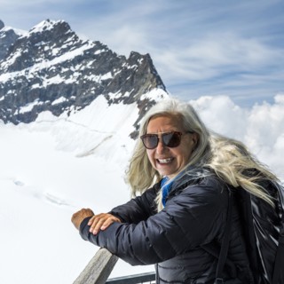 Portrait of smiling Caucasian woman leaning on railing near mountains
