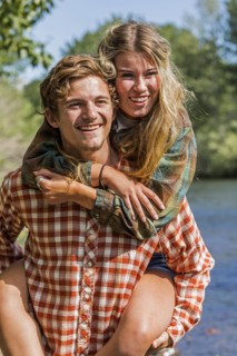 Caucasian boy carrying girl piggyback at river