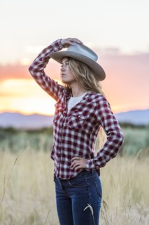 Caucasian teenage girl wearing cowboy hat at sunset