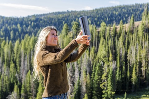 Caucasian girl photographing landscape with digital tablet