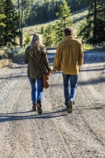 Caucasian couple walking on dirt road holding hands