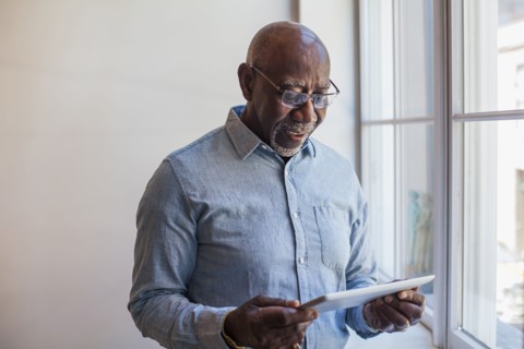 Man using digital tablet near window