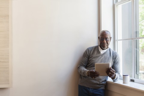 Man using digital tablet near window