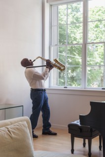 Man playing saxophone near window