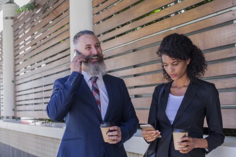 Business people standing outdoors using cell phones