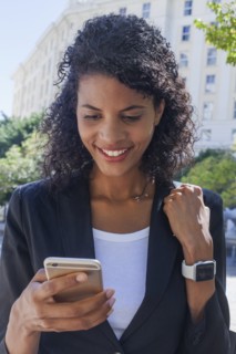Mixed Race businesswoman texting on cell phone outdoors