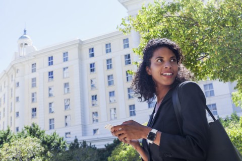 Mixed Race businesswoman texting on cell phone outdoors