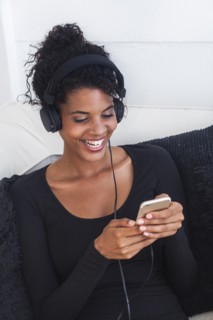 Mixed Race woman listening to cell phone with headphones