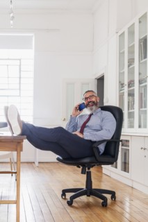 Caucasian man with feet up talking on cell phone