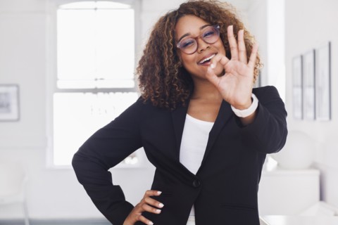 Mixed race woman gesturing okay in gallery